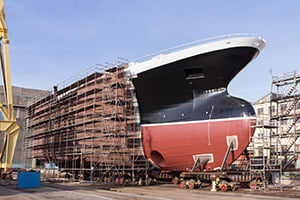 Auch für den Schiffsbau kantet und schneidet Wegener Stahlservice Bauteile. Ein großes Schiff wird von Baugerüsten eingedeckt.